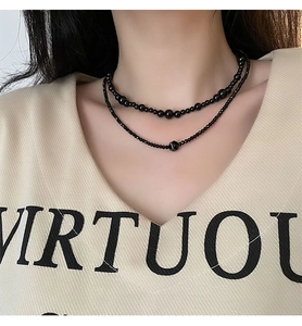 Close-up of double-layer black beaded necklace with gradient round beads and geometric charm