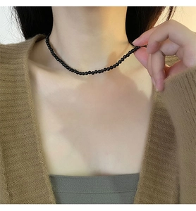 Close-up of a model wearing a minimalist black bead choker necklace with polished finish