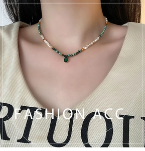 Detail of beaded shell agate necklace with green teardrop pendant on a model