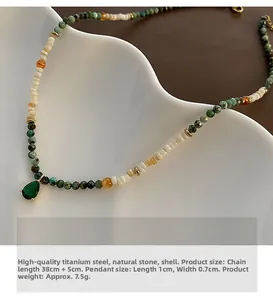 Detail of shell and agate beaded necklace with green drop pendant on a white plate