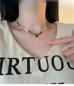 Detail of beaded necklace with green gemstone pendant and natural shells on a model