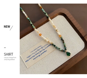 Close-up of shell agate necklace with colorful beads and a dark green gemstone drop