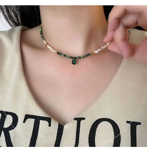 Detailed view of beaded necklace with pearl accents and pear-cut emerald green pendant