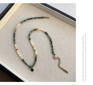 Macro shot of green teardrop pendant and beaded necklace with K18 gold-plated clasp