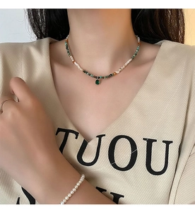 Close-up of bohemian beaded necklace with shell agate stones and teardrop pendant on model