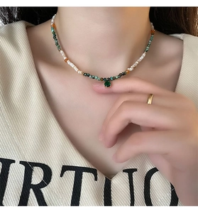 Close-up of beaded necklace with a green teardrop pendant and mixed agate stones
