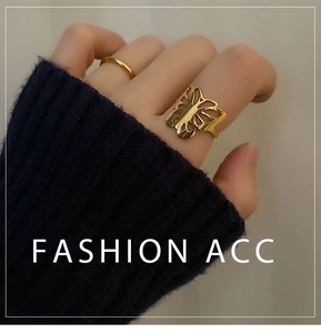 Detail of 18k gold butterfly hollow ring paired with minimalist band on model hand