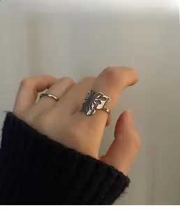 Detail of silver hollow butterfly ring and simple thin band worn on finger