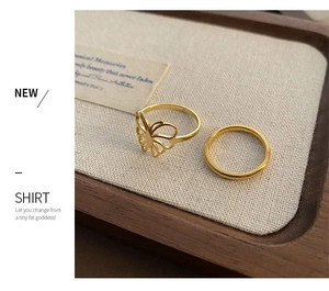 Detail view of 18k gold butterfly ring set on a jewelry tray with woven texture