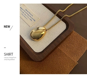Close-up of polished gold teardrop pendant necklace displayed on a luxury jewelry tray