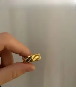 Detailed view of wide gold titanium steel ring with unique vertical pleated texture