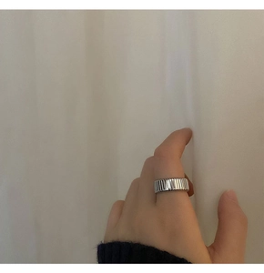 Close-up of silver wide band ring with vertical striped texture on finger