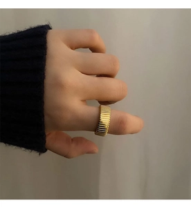 Close-up of golden wide Tubogas snake bone ring worn on finger with ribbed texture