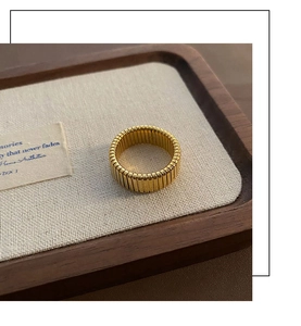 Detailed close-up of a wide gold-plated titanium steel ring with vertical ribbed texture