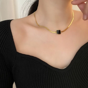 Collier minimaliste en acier titane doré avec pendentif carré noir porté au cou