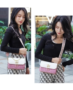 Detail of a pink sequin crossbody bag with pearl cat-ear clasp and ethnic embroidery strap