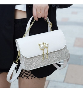 Detail of white leather shoulder bag featuring cat pearl buckle and sequin stitching