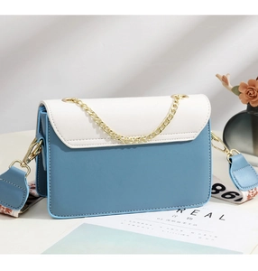 Detail view of the blue and white crossbody bag with decorative chain and patterned strap