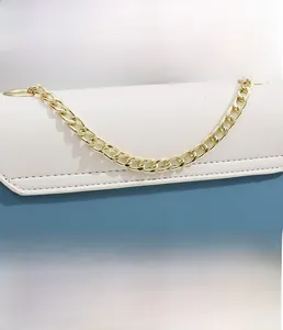 Detail of color-block shoulder bag featuring beige and blue panels with golden chain strap