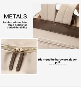 Detail of reinforced shoulder straps and gold dual metal zippers on beige nylon backpack