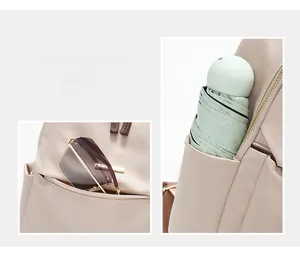 Detail view of the beige backpack featuring side open pockets and gold zipper compartments