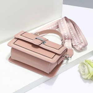 Sac bandoulière rose en similicuir avec sangle tissée sur socle blanc minimaliste