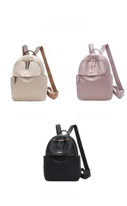 Three lightweight oxford fabric backpacks in khaki, pink, and black with gold zippers