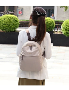 Close-up of beige nylon travel backpack showing textured fabric and gold logo plate