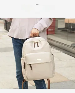 Close-up of beige oxford backpack with brown leather accents and large front zipper pocket