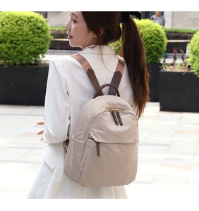 Detail of woman wearing a khaki oxford cloth backpack with brown leather accents