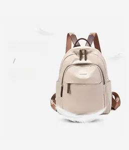 Détail d'un sac à dos léger en oxford beige avec bretelles brunes et plume symbolisant la légèreté