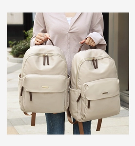 Detail of minimalist beige oxford backpack with golden hardware and brown zipper accents