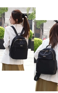 Outdoor lifestyle view of lightweight black Oxford cloth backpack with gold hardware
