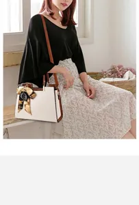 Detail van beige handtas met krokodillenprint, decoratieve zijden sjaal en schouderriem