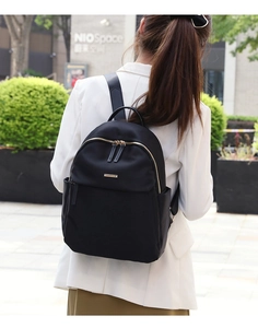 Fashionable black nylon backpack for women with golden zippers in an urban street setting