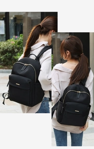 Detail view of lightweight black nylon backpack with gold zippers and side pockets