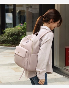 Detail view of pink nylon backpack featuring golden metal zippers and side pocket for commute