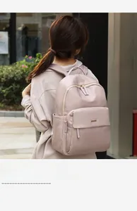 Rear view of a model wearing a pink waterproof nylon backpack with metal logo detail