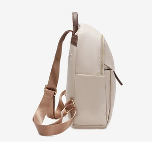 Side view of beige nylon backpack featuring brown leather straps and side pocket details