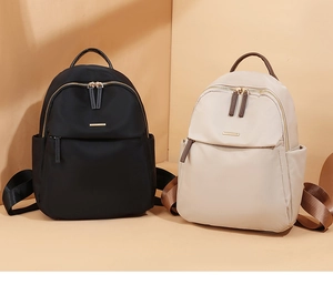 Front view of stylish black and beige nylon backpacks with elegant gold metal zippers