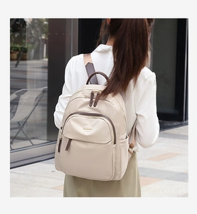 Détail d'un sac à dos en nylon beige avec accents en cuir marron en vue urbaine