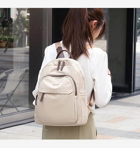Vue de dos d'un mannequin portant un sac à dos en nylon beige dans une rue urbaine