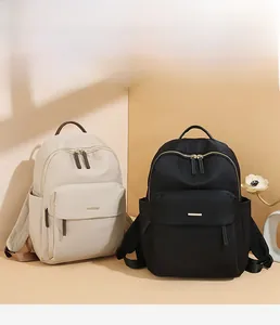 Detail of minimalist waterproof nylon backpacks in black and beige with front zipper pockets