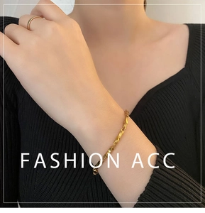 Detailed close-up of golden Mobius twist bracelet and matching minimalist ring on model