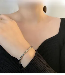 Polished silver Mobius titanium steel bracelet worn on wrist over black knitwear