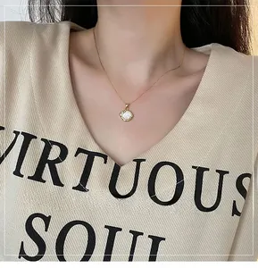 Gros plan du collier avec pendentif coquillage doré sur un mannequin en pull beige