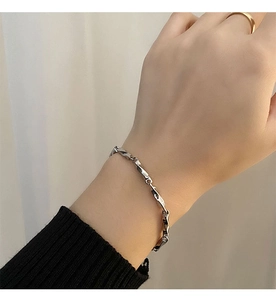 Detail of silver twisted Moebius link bracelet worn on wrist with black knit cuff