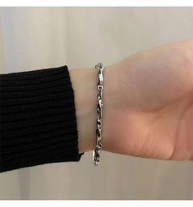 Close-up of Möbius titanium steel twist chain bracelet worn on a wrist with black cuff