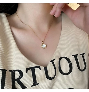 Gros plan d'un collier doré avec pendentif en nacre blanche sur modèle pour style élégant