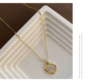 Détail macro du pendentif coquillage doré avec nacre et petite étoile sur chaîne fine